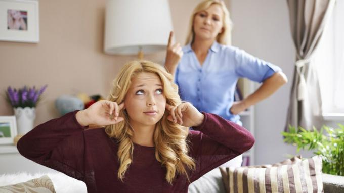 Umbusaldusväärne teismeline tüdruk katab toas sõrmedega kõrvad, kui ema teda karjub